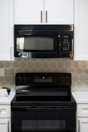 a kitchen with white cabinets and a black stove and microwave